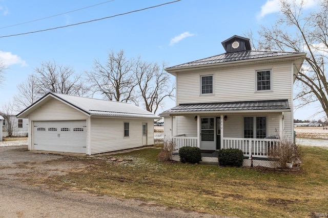 view of front of property featuring covered porch, a garage, a front lawn, and an outdoor structure