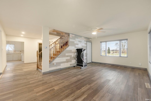 unfurnished living room with ceiling fan, sink, and light hardwood / wood-style flooring