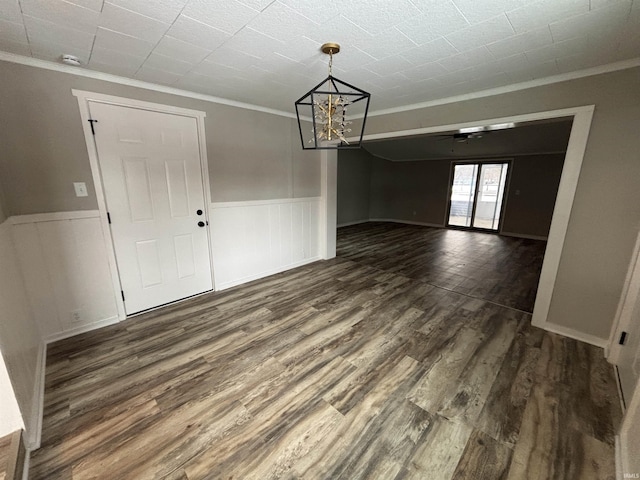 unfurnished dining area with crown molding, dark wood-type flooring, and ceiling fan with notable chandelier