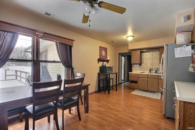 dining space featuring light wood-type flooring, ceiling fan, and sink