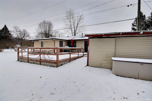 snow covered back of property with a deck