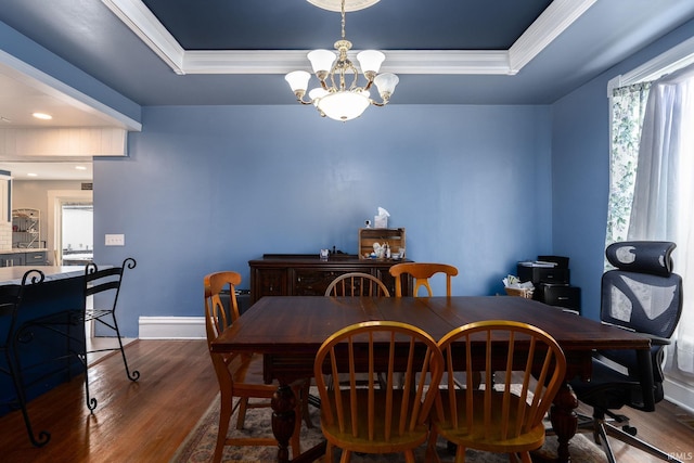 dining space with a raised ceiling, a healthy amount of sunlight, dark wood-type flooring, and a chandelier