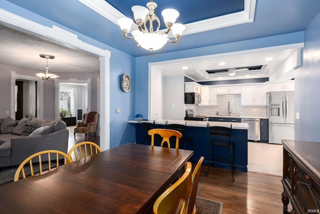 dining room with a chandelier, a tray ceiling, dark wood-type flooring, and sink