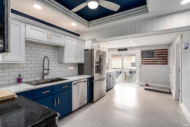 kitchen with appliances with stainless steel finishes, a raised ceiling, sink, blue cabinetry, and white cabinets