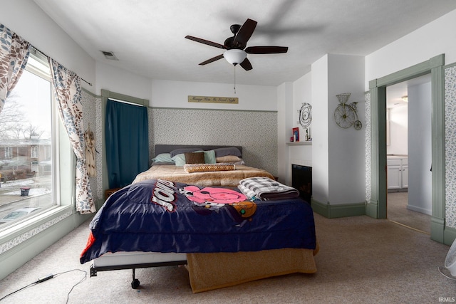 carpeted bedroom with ensuite bath and ceiling fan