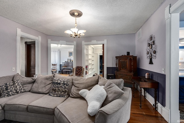 living room with a textured ceiling, a notable chandelier, and dark wood-type flooring