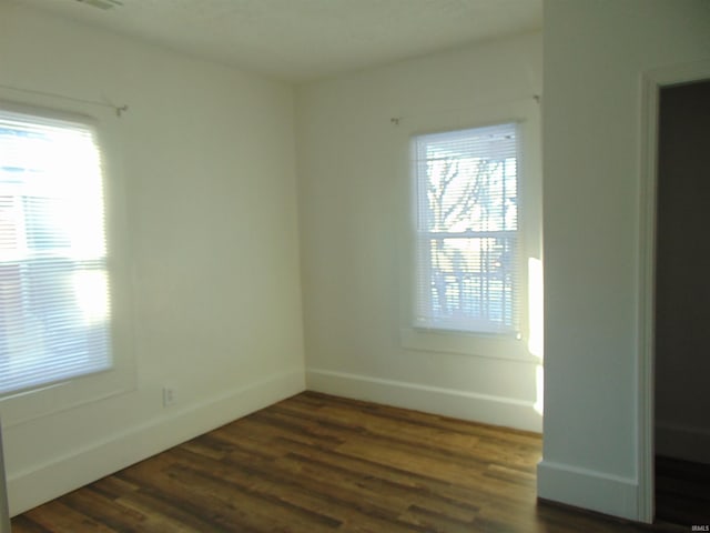 unfurnished room with plenty of natural light and dark wood-type flooring