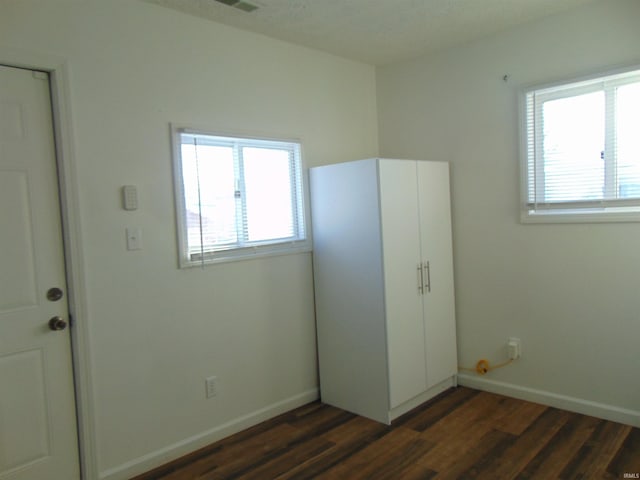 unfurnished bedroom with dark hardwood / wood-style floors and multiple windows