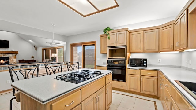 kitchen with black microwave, a center island, stainless steel gas cooktop, a kitchen bar, and a fireplace