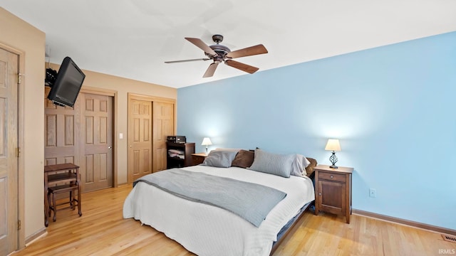 bedroom with multiple closets, ceiling fan, and light hardwood / wood-style floors