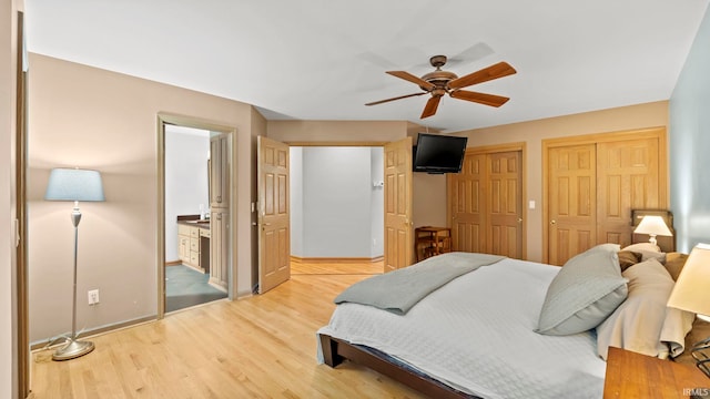 bedroom with ceiling fan, light wood-type flooring, connected bathroom, and two closets