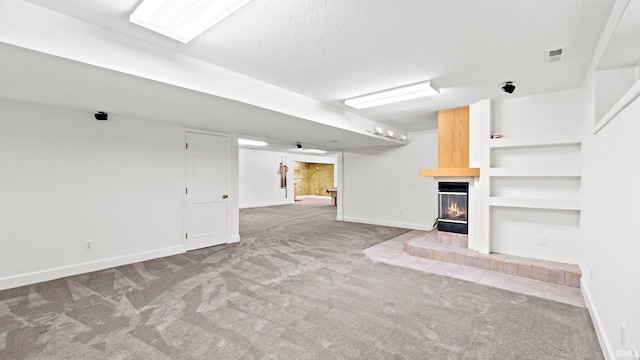 unfurnished living room featuring a multi sided fireplace, a textured ceiling, carpet flooring, and built in features