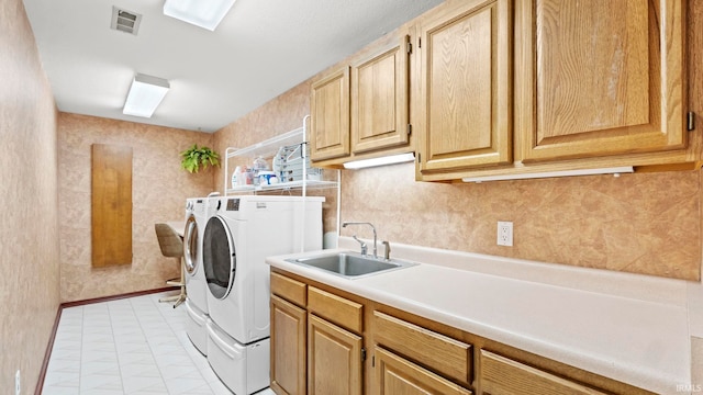 laundry room featuring washing machine and clothes dryer, sink, and cabinets