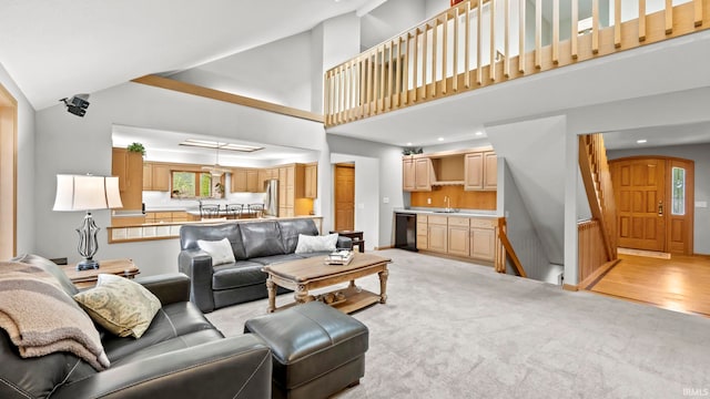 living room featuring light colored carpet, sink, and high vaulted ceiling