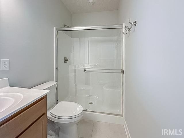 bathroom featuring tile patterned flooring, a textured ceiling, toilet, vanity, and a shower with shower door