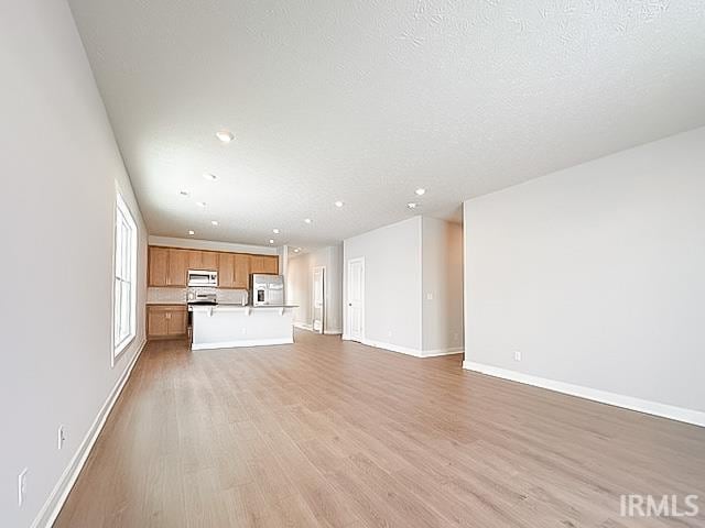 unfurnished living room featuring light hardwood / wood-style floors and a textured ceiling