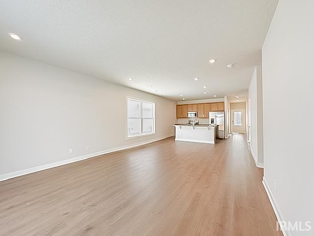 unfurnished living room featuring a textured ceiling and light hardwood / wood-style flooring