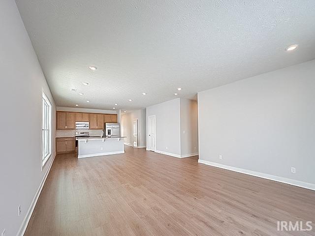 unfurnished living room with a textured ceiling and light hardwood / wood-style flooring