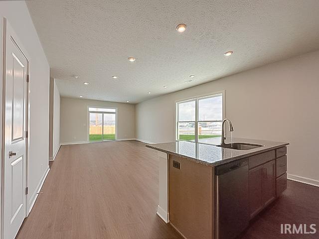 kitchen featuring a textured ceiling, sink, wood-type flooring, a center island with sink, and dishwasher