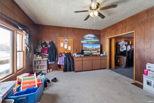 carpeted office with ceiling fan and wooden walls