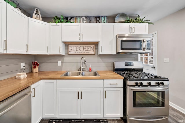 kitchen with butcher block countertops, white cabinets, sink, and appliances with stainless steel finishes