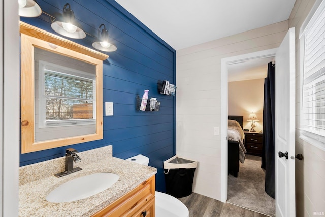 bathroom featuring wood-type flooring, vanity, toilet, and wood walls