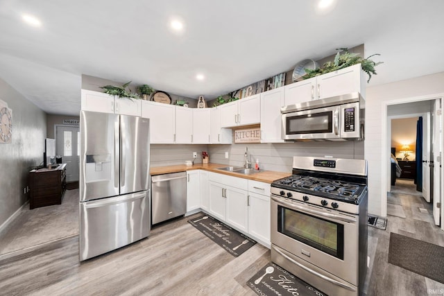 kitchen with white cabinets, butcher block countertops, sink, and stainless steel appliances