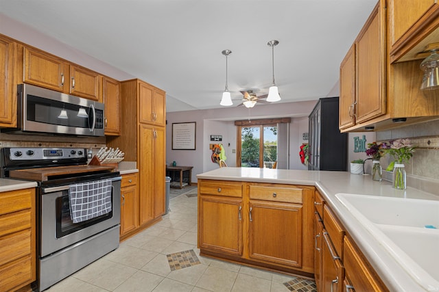 kitchen with backsplash, light tile patterned floors, decorative light fixtures, kitchen peninsula, and stainless steel appliances