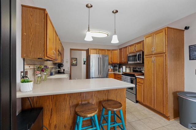 kitchen featuring kitchen peninsula, tasteful backsplash, a breakfast bar, stainless steel appliances, and sink