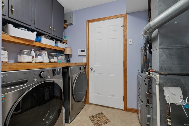 washroom with washing machine and clothes dryer, heating unit, light tile patterned flooring, and cabinets