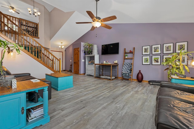 living room featuring ceiling fan with notable chandelier, lofted ceiling, and light hardwood / wood-style flooring