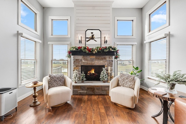 living area with a fireplace, a high ceiling, and dark hardwood / wood-style floors