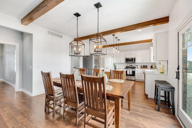 dining area featuring beam ceiling, wood-type flooring, and an inviting chandelier