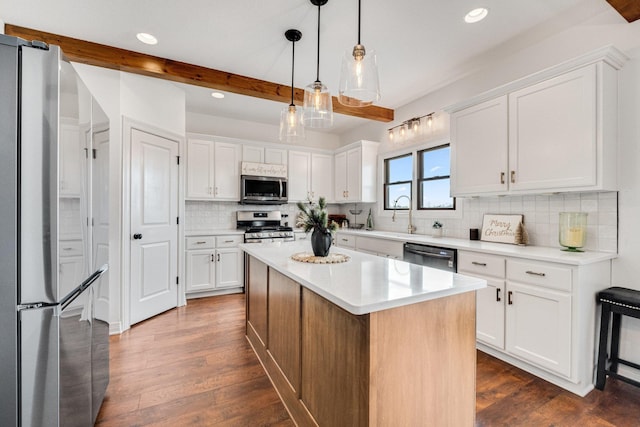 kitchen featuring white cabinets, hanging light fixtures, beam ceiling, appliances with stainless steel finishes, and a kitchen island