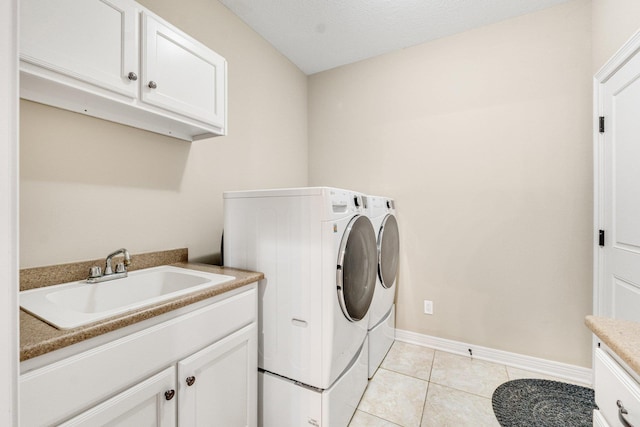 laundry area featuring cabinets, light tile patterned floors, washing machine and dryer, and sink