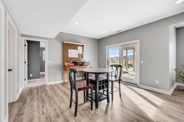 dining area featuring a textured ceiling and light hardwood / wood-style flooring