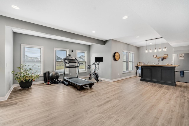 workout room with light hardwood / wood-style floors, wet bar, and track lighting