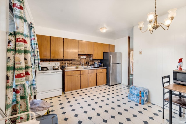 kitchen with pendant lighting, backsplash, sink, appliances with stainless steel finishes, and a chandelier