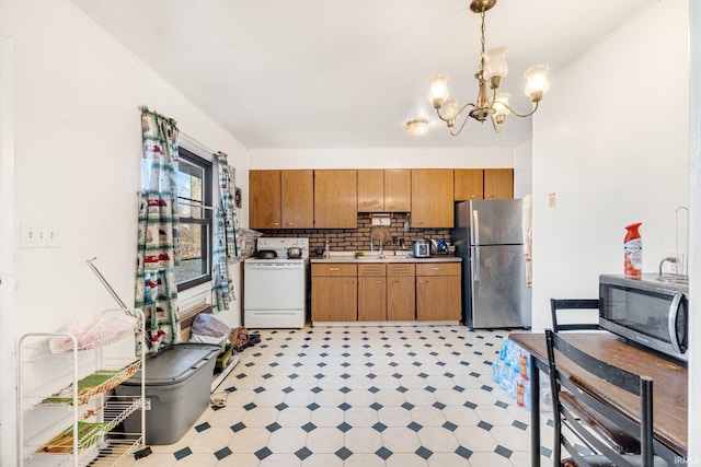 kitchen featuring decorative backsplash, appliances with stainless steel finishes, sink, an inviting chandelier, and hanging light fixtures