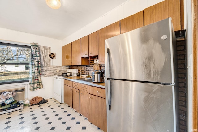 kitchen with backsplash, stainless steel refrigerator, sink, and white electric range