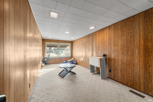 unfurnished room featuring light colored carpet and wood walls