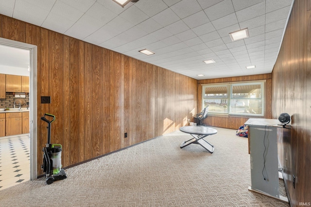 workout room with wooden walls, sink, and light colored carpet