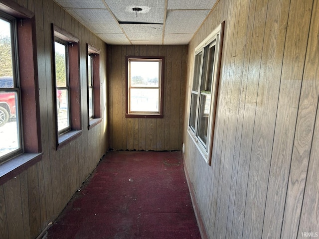 hallway featuring dark colored carpet and wooden walls