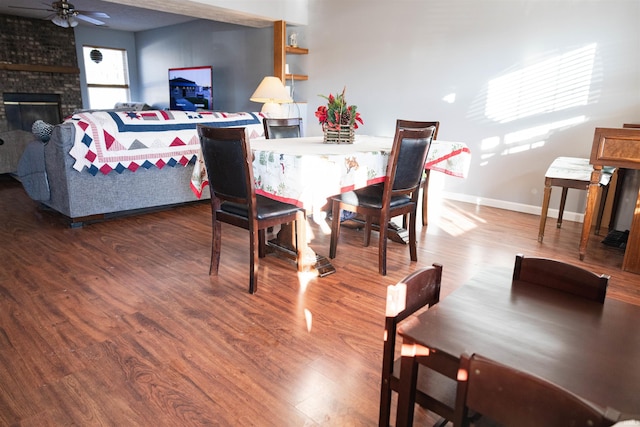 dining area with a fireplace, ceiling fan, and hardwood / wood-style floors