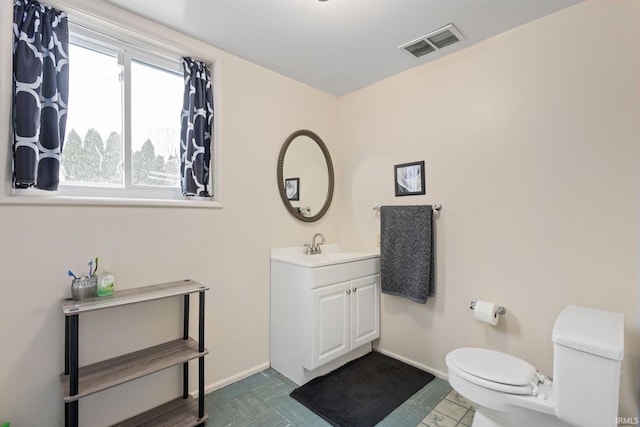 bathroom with vanity, toilet, and a healthy amount of sunlight