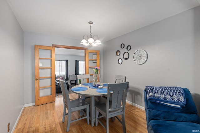 dining space featuring light wood-type flooring and an inviting chandelier