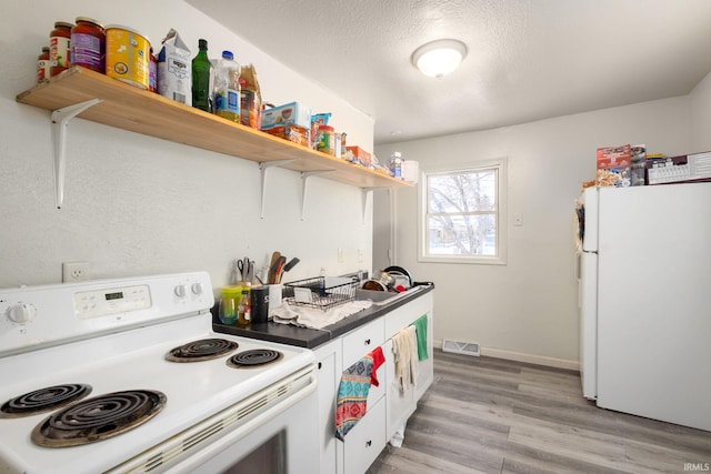 kitchen featuring a textured ceiling, white appliances, light hardwood / wood-style flooring, and white cabinetry