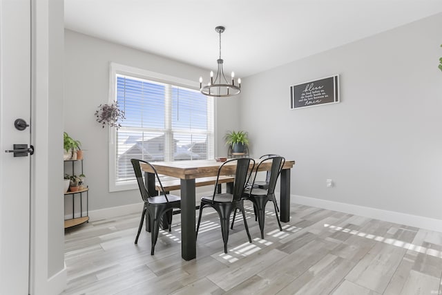 dining space with light wood-type flooring and an inviting chandelier