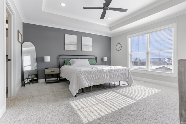 bedroom with a tray ceiling, multiple windows, ceiling fan, and carpet flooring