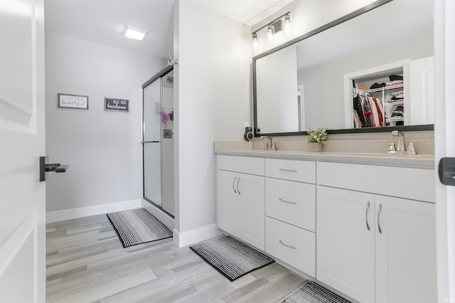 bathroom with a shower with door, vanity, and wood-type flooring